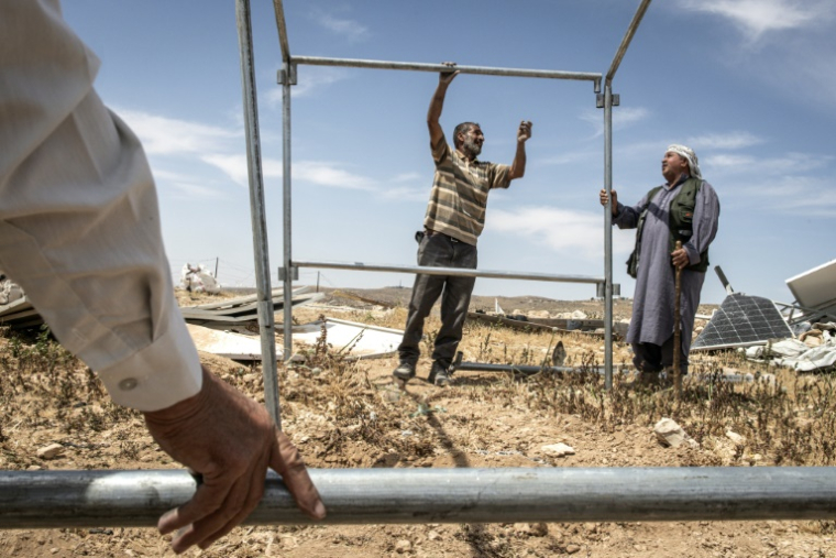 Des Palestiniens montent une tente au milieu des décombres du hameau de Khallet Al-Dabaa, en Cisjordanie occupée, le 6 mai 2025, après la destruction par les forces israéliennes des habitations de ce village ( AFP / JOHN WESSELS )