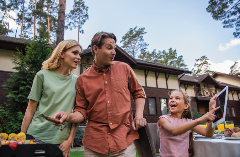 (Crédits photo : Adobe Stock - Des parents préparent un barbecue dans le jardin aux côtés de leur fillette tenant une tablette numérique)