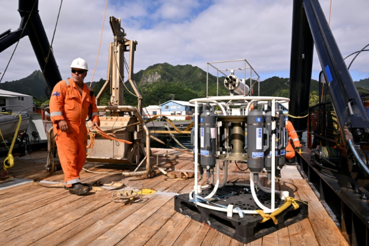 Un membre d'équipage à côté d'équipement sd'exploitation minière en haute mer sur le pont du navire de recherche Anuanua Moana, le 11 juin 2025 à Rarotonga, aux îles Cook ( AFP / William WEST )