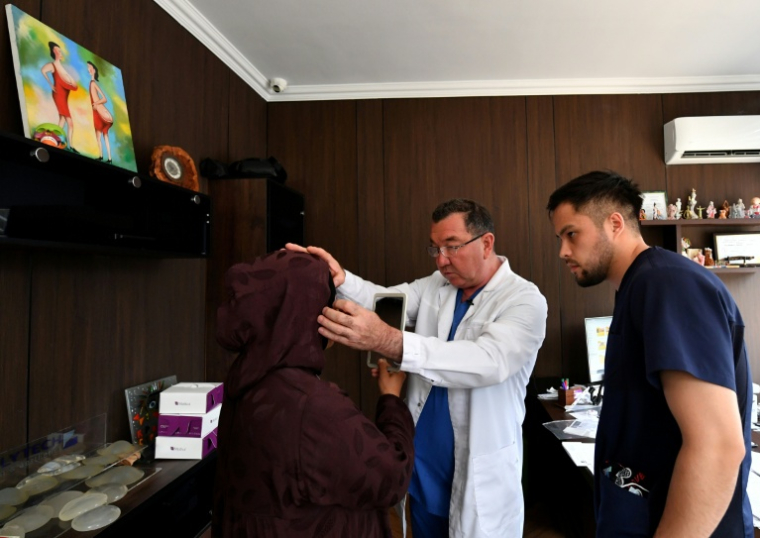 Le chirurgien esthétique Iskender Katchkinbaïev examine une patiente à Bichkek, le 18 mai 2026 au Kirzghizstan ( AFP / Vyacheslav OSELEDKO )