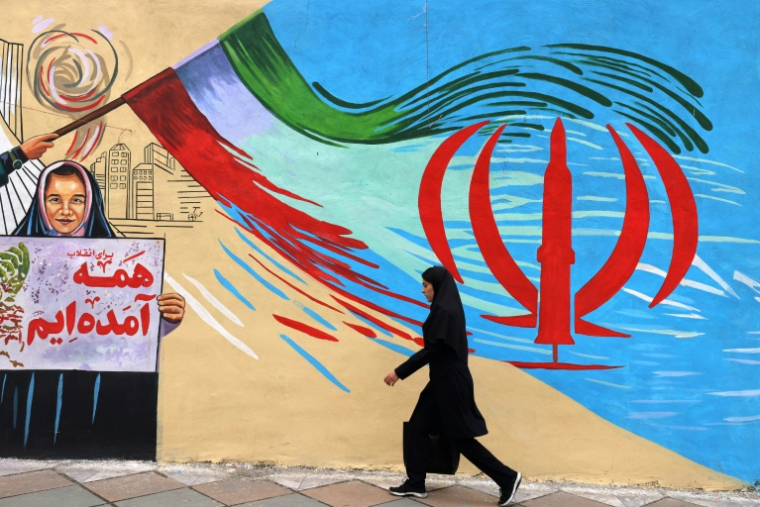 Une femme marche devant une fresque murale contre Israël et les Etats-Unis, à Téhéran le 21 avril 2026. ( AFP / ATTA KENARE )