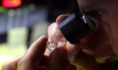 Un employé examine un diamant brut à l'usine "Flanders Manufacturing"