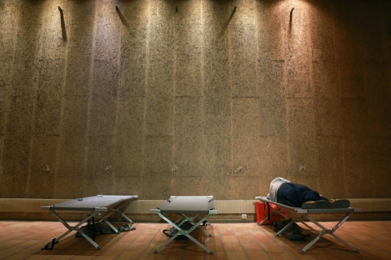 Une personne se repose sur un lit de camp au centre d'accueil Jean Moulin à Bordeaux, le 11 août 2025 ( AFP / ROMAIN PERROCHEAU )