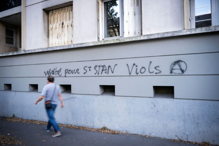 Un homme passe devant un graffiti dans une rue proche de l'entrée du lycée privé catholique et du Collège Saint-Stanislas à Nantes, le 29 août 2025 ( AFP / Loic VENANCE )