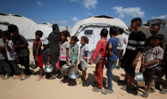 Des Palestiniens attendent de recevoir de la nourriture préparée par une cuisine caritative près des tentes où ils ont trouvé refuge après avoir été déplacés par l'offensive militaire israélienne, à Gaza