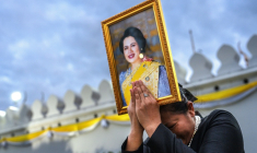 Une femme endeuillée tient un portrait de la reine mère Sirikit de Thaïlande au passage du cortège funéraire, le 26 octobre 2025 à Bangkok ( AFP / Chanakarn Laosarakham )