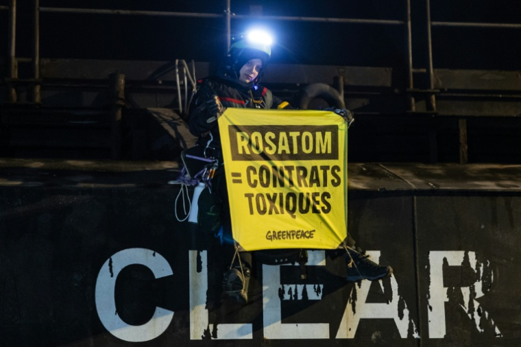Un militant tient une banderole "Rosatom = contrats toxiques" lors d'une opération de Greenpeace visant à bloquer le cargo Mikhail Dudin à Dunkerque,  le 2 mars 2026 dans le Nord ( AFP / Sameer Al-DOUMY )