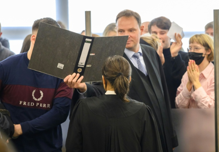 Un des sept accusés du procès du groupe Antifa Ost, le visage caché par son avocat, le 25 novembre 2025 à Dresde ( POOL / MATTHIAS RIETSCHEL )