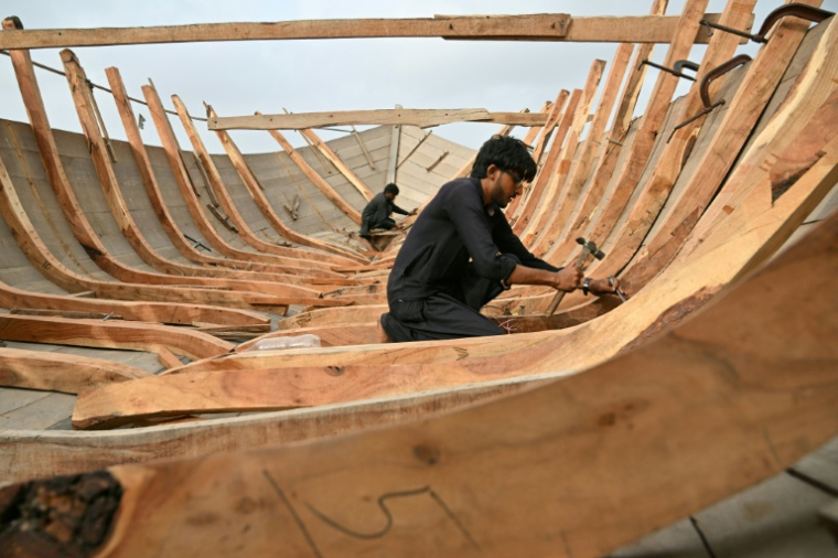Des artisans construisent un bateau traditionnel en bois dans le quartier Ibrahim Hyderi, à Karachi, Pakistan, le 8 juillet 2026  ( AFP / Asif HASSAN )
