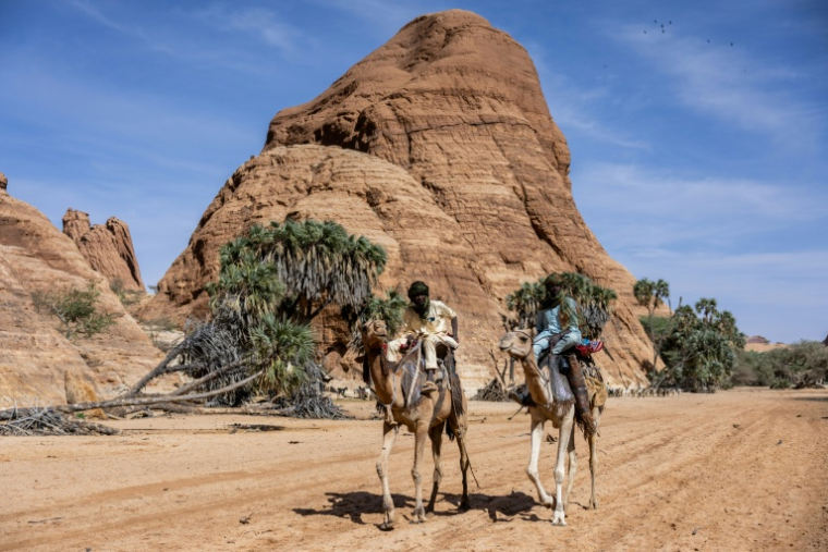 Deux hommes montent à dos de chameau dans le Guelta de Bachikele, une oasis saharienne située dans le nord du Tchad, le 11 février 2026 ( AFP / Joris Bolomey )
