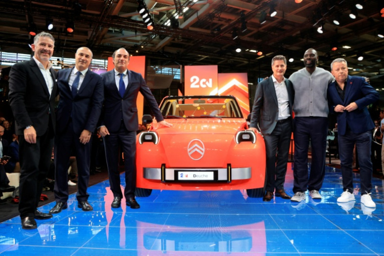 Les dirigeants de Stellantis et Citroën posent avec le comédien Omar Sy devant la nouvelle 2CV électrique au Mondial de l’Auto à Paris, le 12 octobre 2026 ( AFP / Ludovic MARIN )