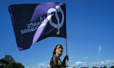 Une sympathisante de La France insoumise (LFI) tient un drapeau lors des universités d'été du parti (LFI), le 22 août 2026 à  Châteauneuf-sur-Isère, dans la Drôme  ( AFP / OLIVIER CHASSIGNOLE )