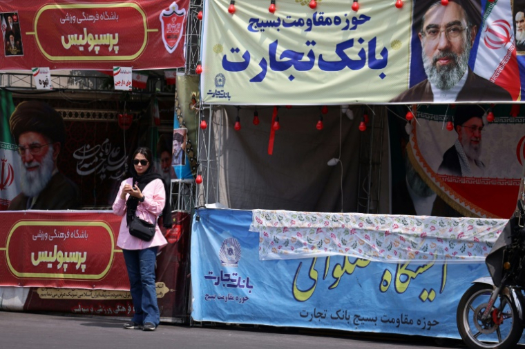 Une femme se tient sous une bannière représentant le guide suprême de l'Iran, l'ayatollah Mojtaba Khamenei, dans une rue de Téhéran, le 2 mai 2026 ( AFP / - )