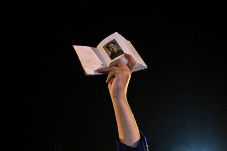 Un homme brandit un livre avec un portrait du dirigeant communiste Mao Zedong à Shaoshan en Chine, le 8 septembre 2026 ( AFP / Hector RETAMAL )