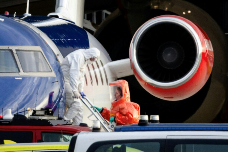Une personne vêtue d'une combinaison de protection descend d'un avion médicalisé transportant des passagers du bateau de croisière MV Hondius, soupçonnés d'être infectés par le hantavirus, avant d'être escortée vers une ambulance à l'aéroport de Schiphol, le 6 mai 2026 à Amsterdam, aux Pays-Bas  ( ANP / Jeffrey Groeneweg )