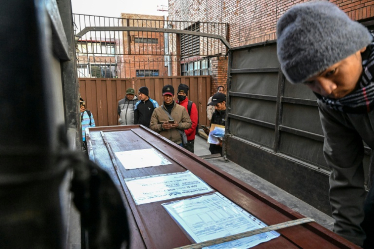 Lalit Bishowkarma (c) devant le cercueil contenant la dépouille de son père Rudra Bahadur Kami, le 21 janvier 2026 à l'aéroport de Katmandou, au Népal ( AFP / Prakash MATHEMA )