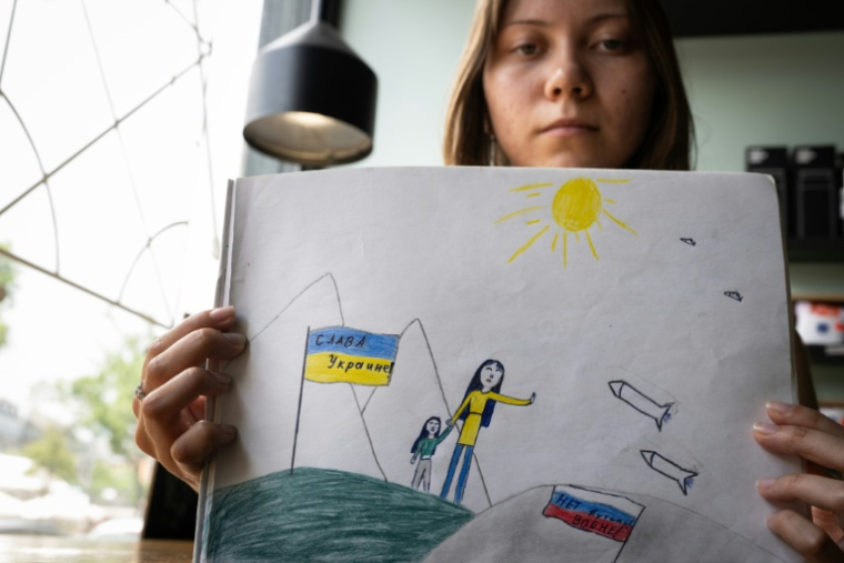Maria Moskalyova pose avec le dessin anti-guerre qu'elle a réalisé dans son école russe, à Strasbourg, le 6 juin 2026 ( AFP / SEBASTIEN BOZON )