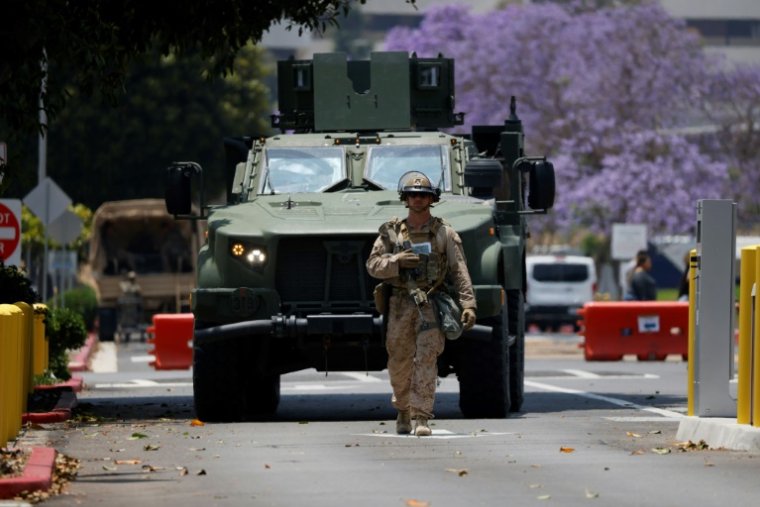 Un Marine marche devant un véhicule blindé dans le quartier de Westwood à Los Angeles le 13 juin 2025. ( AFP / Etienne LAURENT )