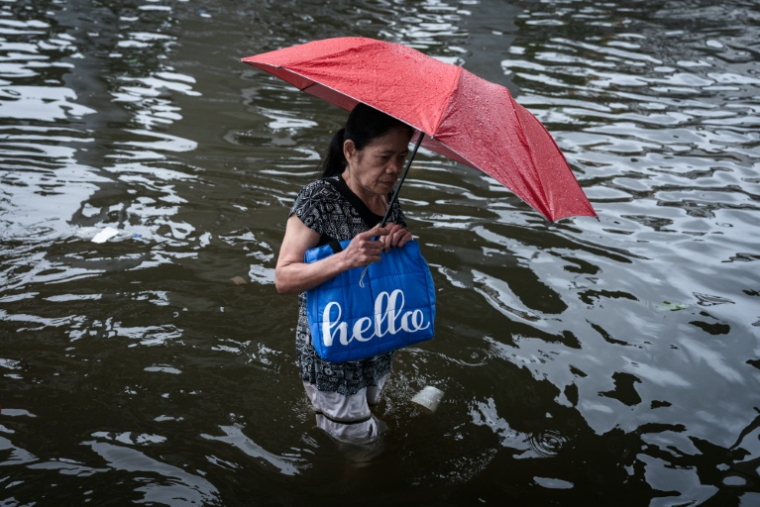 Une femme se fraye un chemin dans une rue inondée de Bangkok, où l'état de catastrophe naturelle a été déclaré après des pluies diluviennes qui ont inondé habitations, commerces et axes de circulation, le 27 septembre 2026 ( AFP / Chanakarn LAOSARAKHAM )