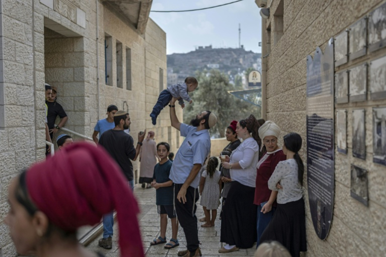 Israeli settlers wait outside a polling station in the occupied West Bank city of Hebron on October 27, 2026 during Israel's legislative election.  ( AFP / Ilia YEFIMOVICH )