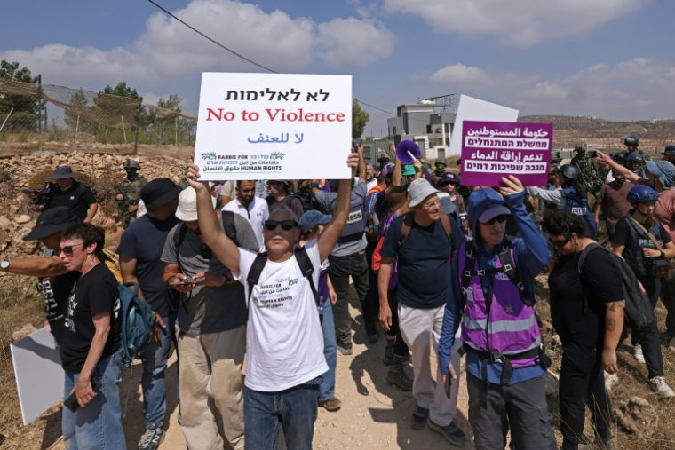 Des militants israéliens et des bénévoles solidaires rassemblés devant une maison palestinienne assiégée par des colons israéliens dans le village de Qusra, au sud de Naplouse, en Cisjordanie occupée, le 14 août 2026 ( AFP / JAAFAR ASHTIYEH )