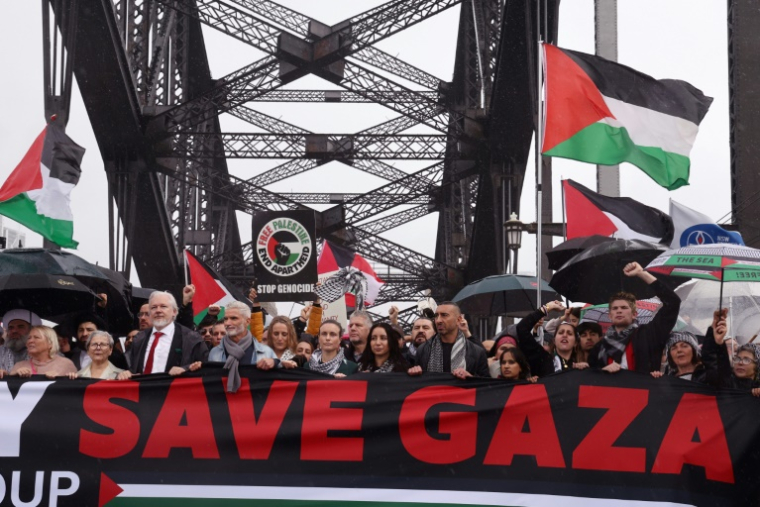 Des manifestants, dont le fondateur de WikiLeaks, Julian Assange (3e en partant de la gauche, l'homme portant une cravate rouge), défilent sur le pont Harbour Bridge à Sydney lors d’un rassemblement pro-palestinien le 3 août 2025. ( AFP / David GRAY )