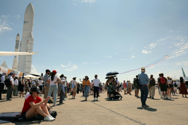 Des visiteurs regardent des avions de la patrouille de France pendant la 55e édition du Salon international de l'aéronautique et de l'espace à l'aéroport du Bourget, au nord de Paris, le 20 juin 2025 ( AFP / Thomas SAMSON )