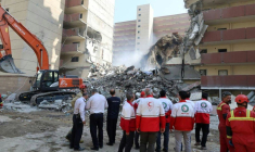 Photo diffusée par le Croissant-Rouge iranien le 14 juin 2025 montrant des bénévoles rassemblés devant un bâtiment détruit lors d'une frappe israélienne à Téhéran ( Iranian Red Crescent / - )
