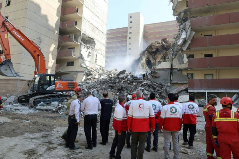 Photo diffusée par le Croissant-Rouge iranien le 14 juin 2025 montrant des bénévoles rassemblés devant un bâtiment détruit lors d'une frappe israélienne à Téhéran ( Iranian Red Crescent / - )