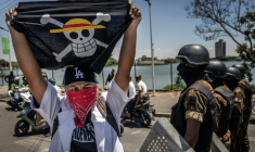 Un drapeau portant le logo du célèbre manga japonais One Piece, symbole adopté par les mouvements de protestation de la génération Z dans le monde entier, devant les forces de sécurité lors d'une manifestation exigeant de meilleures conditions de santé et des réformes constitutionnelles à Antananarivo, le 7 octobre 2025 à Madagascar ( AFP / Luis TATO )