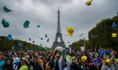Des enfants jettent leur casquette alors qu'ils assistent à un concert au Champ-de-Mars avec la Tour Eiffel en arrière-plan à Paris, dans le cadre de la 46e édition d'une journée d'activités pour les enfants qui ne partent pas en vacances, organisée par le Secours Populaire ( AFP / Dimitar DILKOFF )