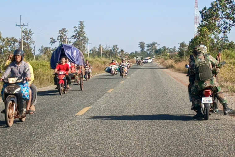 Des soldats cambodgiens (d) circulent à moto tandis que des habitants évacuent les lieux après des affrontements le long de la frontière entre le Cambodge et la Thaïlande, dans la province de Preah Vihear, le 8 décembre 2025 au Cambodge ( AFP / STR )