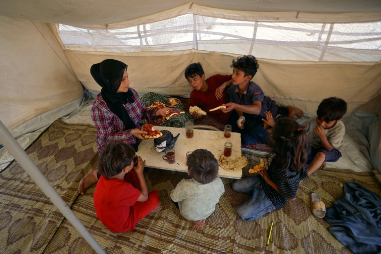 Randa Musleh, 44 ans, nourrit ses enfants dans une tente montée au milieu du cimetière de Kahn Younès dans le sud de la bande de Gaza, le 25 septembre 2025. ( AFP / Omar AL-QATTAA )