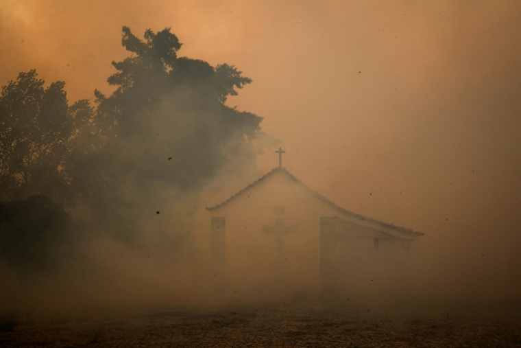 Une chapelle apparait entourée de fumée lors d'un incendie dans le village d'Antas, le 15 août 2025, au Portugal ( AFP / PATRICIA DE MELO MOREIRA )