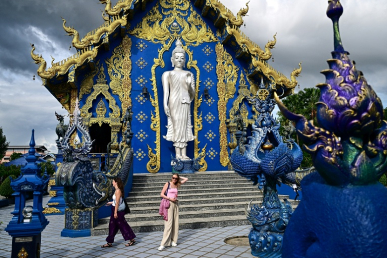 Des touristes visitent le temple bouddhiste Wat Rong Suea Ten, dit "Temple Bleu", dans la province de Chiang Rai, au nord de la Thaïlande, le 26 mai 2025 ( AFP / MANAN VATSYAYANA )