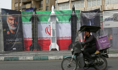 Un homme passe en cyclomoteur devant des répliques de missiles installées sur un trottoir à Téhéran, le 22 mars 2026  ( AFP / - )