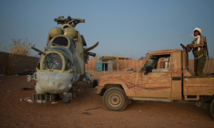 Un combattant du Front de libération de l'Azawad (FLA), rébellion à dominante touareg, se tient sur un pick-up à côté d'une carcasse d'hélicoptère russe Mi-24 dans l'ancien camp du groupe paramilitaire russe Africa Corps à Kidal (Mali), le 6 mai 2026 ( AFP / - )