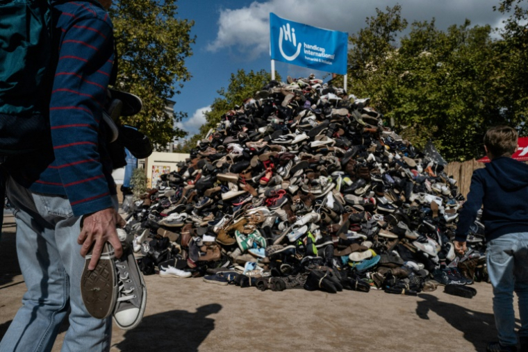 Des personnes jettent des chaussures à l'occasion du 30e anniversaire de la pyramide de chaussures de Handicap international (HI), le 27 septembre 2025 à Lyon ( AFP / JEFF PACHOUD )