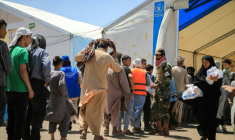 Des réfugiés afghans, expulsés d'Iran, font la queue pour recevoir des colis alimentaires au poste frontière d'Islam Qala, dans la province de Hérat, le 24 juillet 2025 en Afghanistan ( AFP / Mohsen KARIMI )