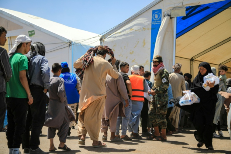 Des réfugiés afghans, expulsés d'Iran, font la queue pour recevoir des colis alimentaires au poste frontière d'Islam Qala, dans la province de Hérat, le 24 juillet 2025 en Afghanistan ( AFP / Mohsen KARIMI )