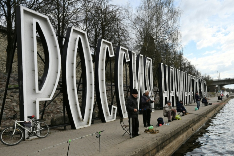 Des pêcheurs devant des lettres géantes "La Russie commence ici" sur la rivière Velikaïa à Pskov, le 17 avril 2026 en Russie (  / Olga MALTSEVA )
