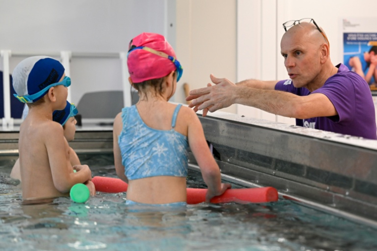 Le maître-nageur Marc Levy apprend la natation à de jeunes enfants dans le camion-psicine du départemebnt de Moselle, le 30 janvier 2026 à Verny ( AFP / Jean-Christophe VERHAEGEN )