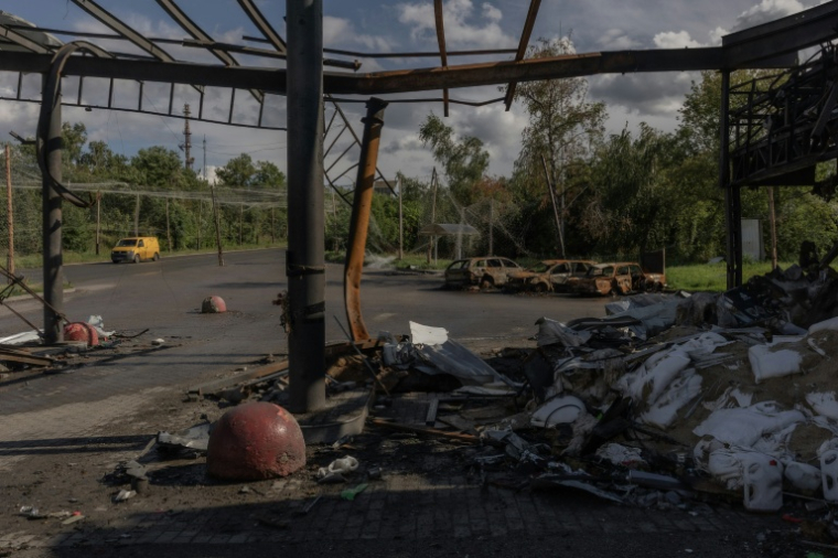 Une voiture passe devant une station-service et des véhicules détruits lors d'une frappe aérienne russe dans la ville d'Izioum, dans la région de Kharkiv, à l'est de l'Ukraine, le 29 juillet 2026 ( AFP / Roman PILIPEY )