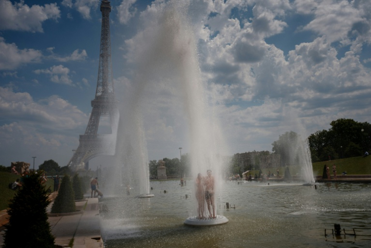 Un couple se rafraîchit sous les jets d'eau de la fontaine du Trocadéro, le 26 juin 2026 à Paris, lors d'un épisode de canicule en France ( AFP / Dimitar DILKOFF )
