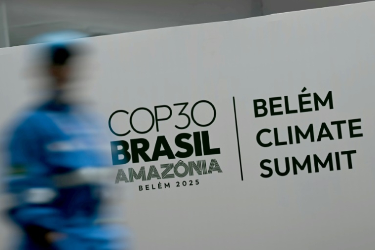 Une personne passe devant une affiche de la COP 30, à Belem au Brésil, le 5 novembre 2025 ( AFP / Mauro PIMENTEL )