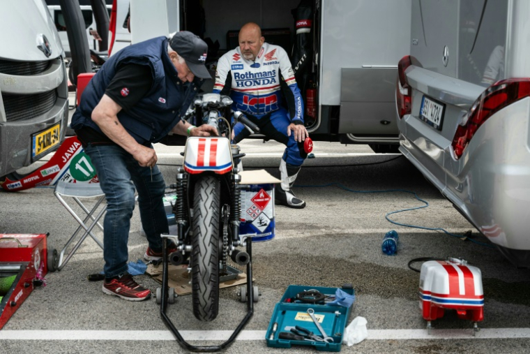 Un motard inspecte sa moto vintage avant de participer à la course "Moto Legende" sur le circuit de Dijon-Prenois, le 25 mai 2025 à Prenois, en Côte-d'Or ( AFP / ARNAUD FINISTRE )