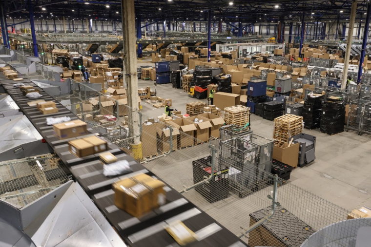 Un employé de la société de livraison de colis Mondial Relay passe devant des colis empilés sur le site situé à Harnes (Pas-de-Calais), le 5 décembre 2023.  ( AFP / DENIS CHARLET )