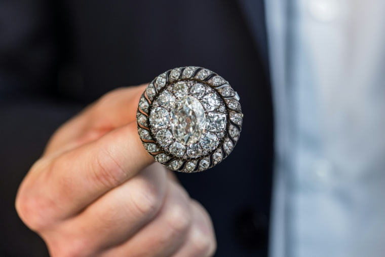 Un employé de Sotheby's présente une broche circulaire ornée de diamants anciens ayant appartenu à Napoléon Bonaparte et récupérée par l'armée prussienne après la défaite de Waterloo, avant une vente aux enchères à Genève, le 6 novembre 2025 ( AFP / PIERRE ALBOUY )