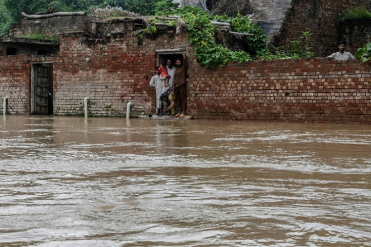 Des villageois dans leur maison partiellement submergée par les eaux de crue après de fortes pluies dans le district de Kasur, au Pakistan, le 24 août 2025 ( AFP / Arif ALI )