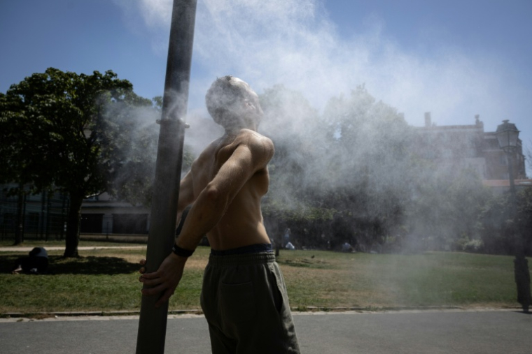 Un homme se rafraîchit sous une fontaine à Paris le 24 juin 2026  ( AFP / Simon WOHLFAHRT )